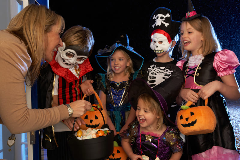 Halloween, foto de mulher dando doces para crianças fantasiadas