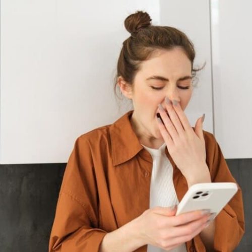 foto de mulher segurando o celular e bocejando